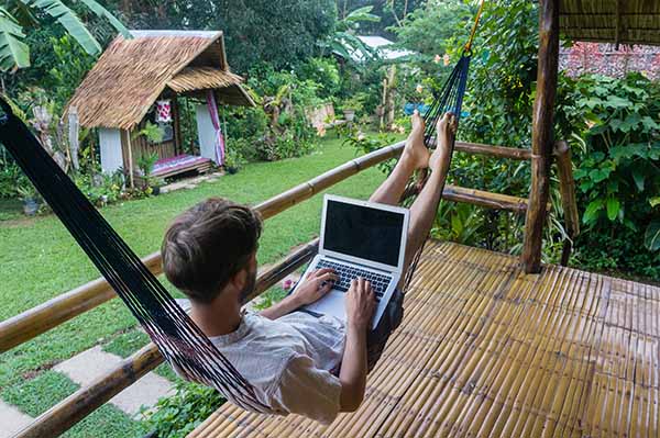 No Office Required: Man on laptop lying in a hammock